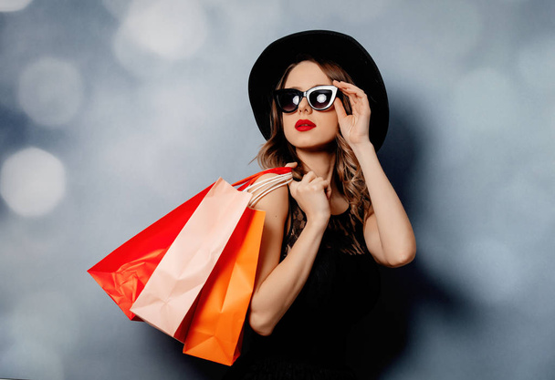 Στυλ γυναίκα σε γυαλιά ηλίου με τσάντες ψώνια σε γκρι φόντο  - Φωτογραφία, εικόνα