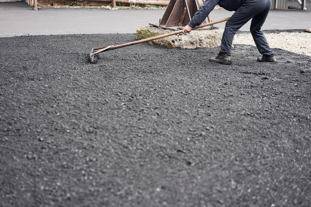 Pose d'asphalte neuf, couvrant la fosse, sur les décombres. Les travailleurs transportent des pelles et utilisent du luth d'asphalte pour obtenir de l'asphalte lisse et chaud
. - Photo, image