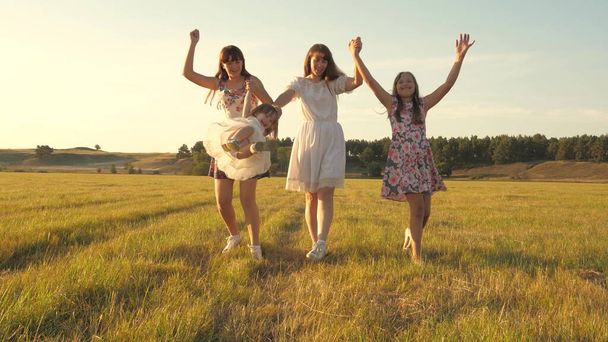 mother and little daughter with sisters walking in park. Happy young family with a child walking on a summer field. Children and mom are playing in the meadow. concept of a happy family. - Photo, Image