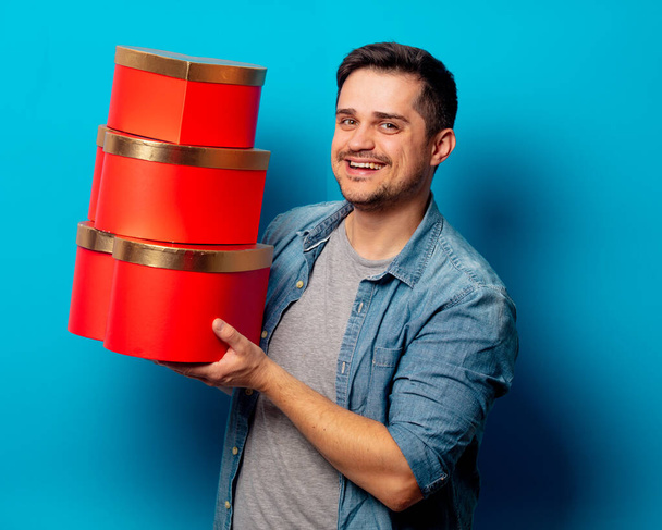 jóképű férfi piros ajándékok kék háttér  - Fotó, kép