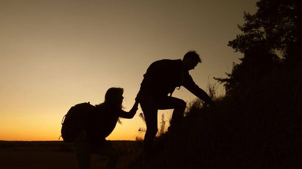 tourists go down from the goy in the sunset, holding hands. male traveler holds the hand of a female traveler going down from top of the hill. teamwork of business people. Happy family on vacation. - Photo, Image