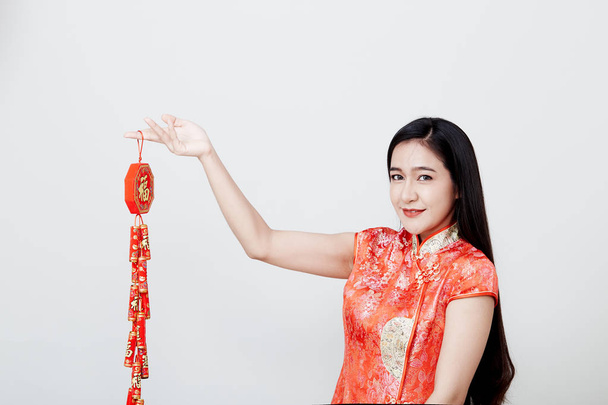 Beautiful girl in red cheongsam holding fire crackers - Photo, Image