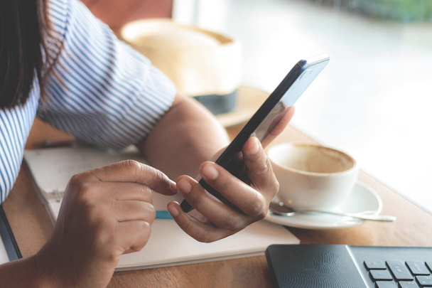 Kobieta wpisując SMS na smartfonie w kawiarni.  - Zdjęcie, obraz