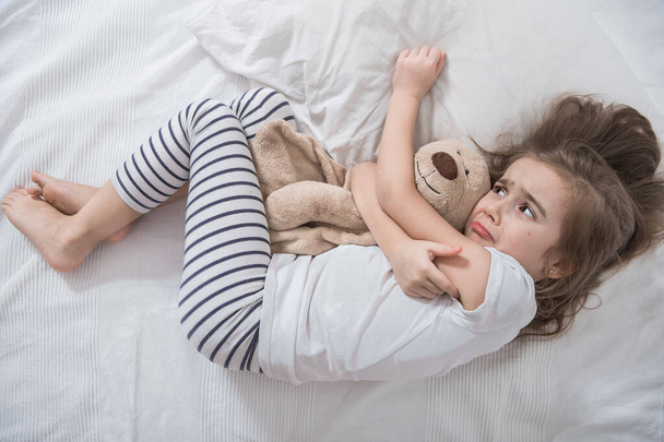 niedliches kleines Mädchen im Bett mit Plüschtier. - Foto, Bild