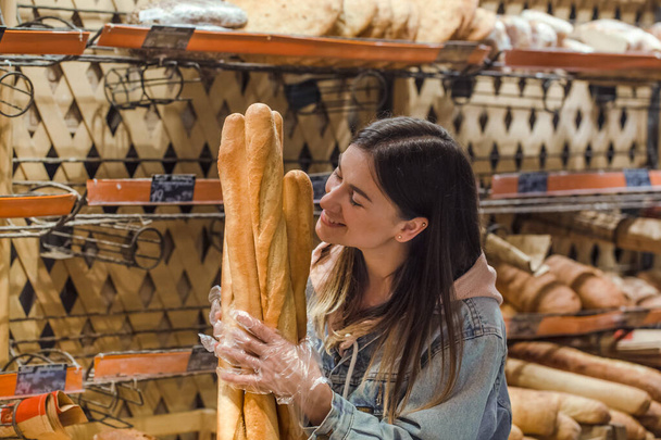 Young woman in supermarket with fresh bread . - Foto, imagen