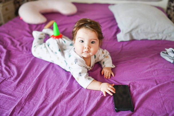 little boy holds a phone. Cute little baby holds mobile phone in his hands and looking attentively at screen. Child and gadget, parent control concept  - 写真・画像