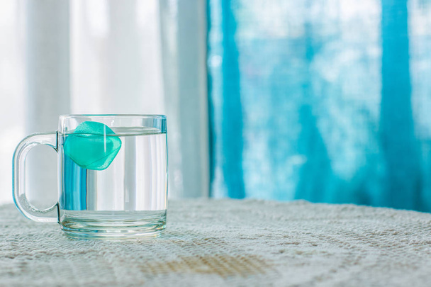 вода з льодом в чашці на столі білий інтер'єр і сині штори не орієнтований фон, теплий літній сезон концептуальна фотографія, порожнє місце для тексту
  - Фото, зображення