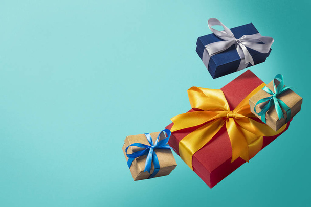 fliegende Geschenkboxen auf blauem Hintergrund. Ferienkonzept, Weihnachten. Schweben. Gegenstände in der Luft. flache Lage, Draufsicht - Foto, Bild