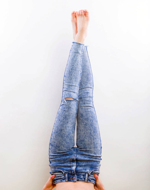 Демонстрация ножек женских джинсов без обуви, студийная съемка на сером фоне крупным планом
 - Фото, изображение
