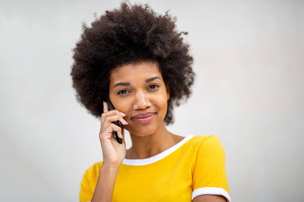 Güzel siyahi bir kadının beyaz arka planda cep telefonuyla konuştuğu portreyi yakından çek.  - Fotoğraf, Görsel