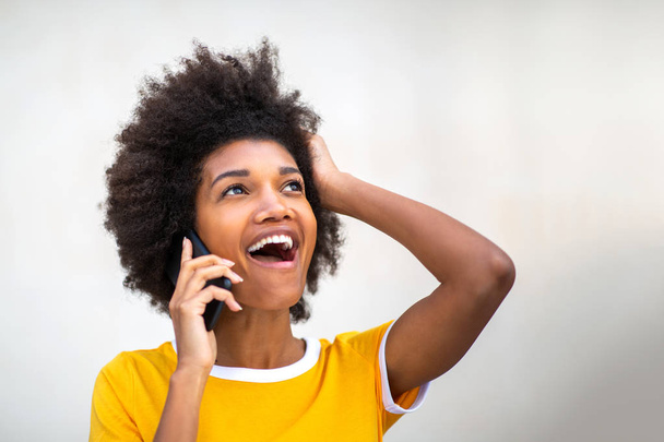 De cerca retrato de hermosa sonriente joven mujer negra hablando con el teléfono celular por el fondo blanco y mirando hacia otro lado
 - Foto, Imagen