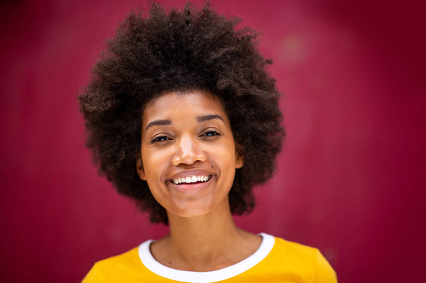 Закройте горизонтальный портрет красивой молодой черной женщины с афро-прической, улыбающейся
 - Фото, изображение