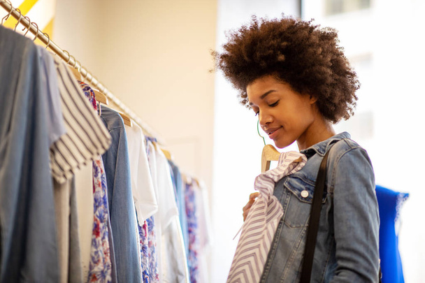 Retrato lateral de una hermosa joven comprando ropa en la tienda
 - Foto, Imagen