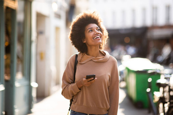 Retrato de una hermosa joven negra con celular caminando por la ciudad
 - Foto, imagen