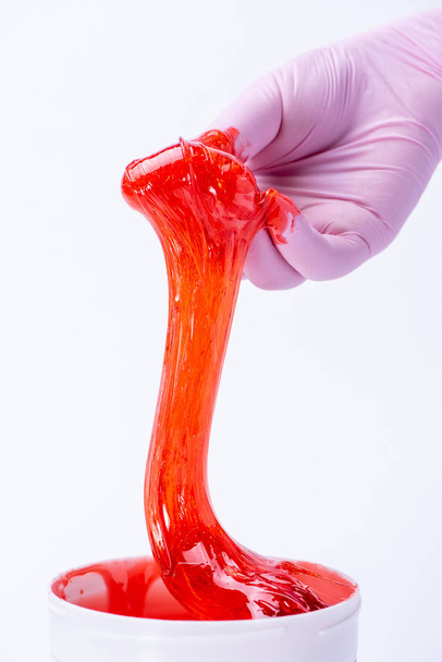Woman's hand in a glove holds red sugar paste or wax for depilat - Foto, imagen