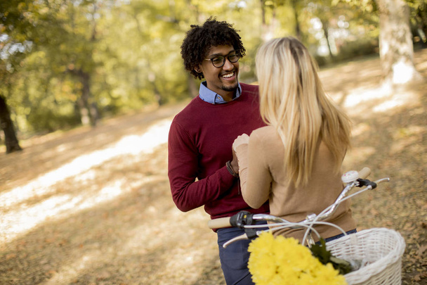 Jeune couple multiracial avec vélo debout dans le parc d'automne
 - Photo, image