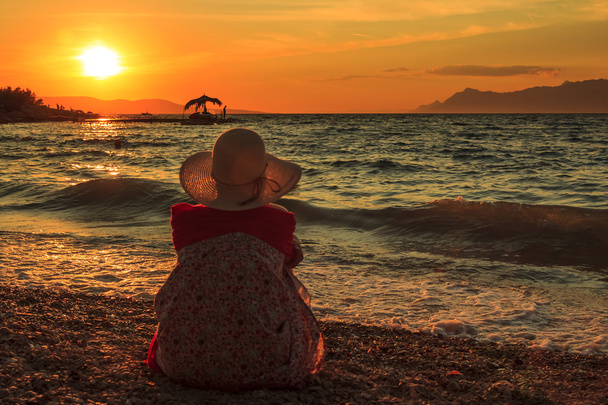 Gondolkodó nő ül a naplemente a strandon - Fotó, kép
