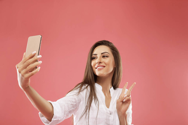 Close up portrait of young beautiful stylish woman making selfie, using her own smartphone, smiles at camera, photo for social networks. - Foto, immagini