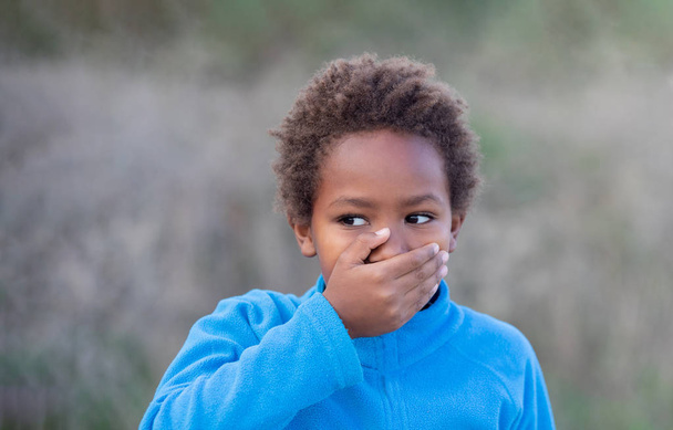 Pieni afrikkalainen poika peittää suunsa.
   - Valokuva, kuva