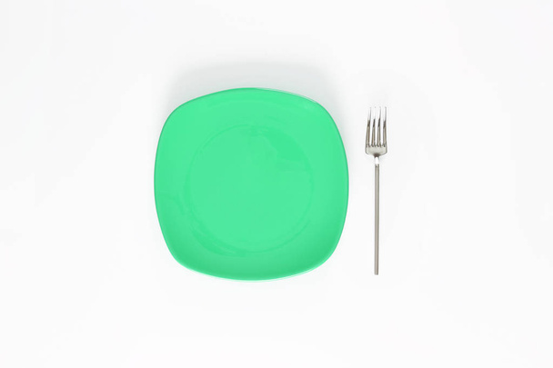 Prázdný Střední Jarní Zelený barevný talíř a vidlička vedle něj. Izolovaný objekt - na bílém pozadí. - Fotografie, Obrázek