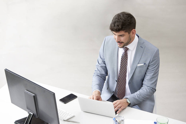 Businessman sitting at office desk and working on laptop - Fotó, kép