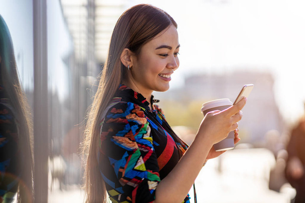 Attraente giovane donna con smartphone e caffè in città
  - Foto, immagini