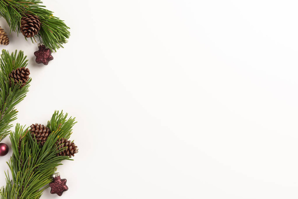 Kerstcompositie. Spar takken met kegels en kerstversieringen, op een witte achtergrond. Kerstmis, winter, nieuwjaarsconcept. Vlakke lay, bovenaanzicht, kopieerruimte. - Foto, afbeelding