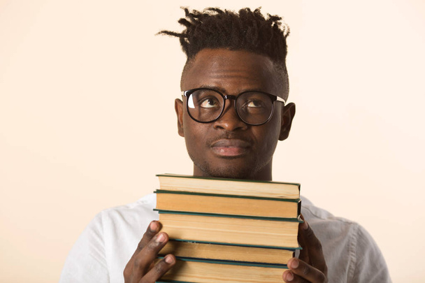 Gözlüklü, beyaz gömlekli, elinde kitap olan yakışıklı bir Afrikalı. - Fotoğraf, Görsel