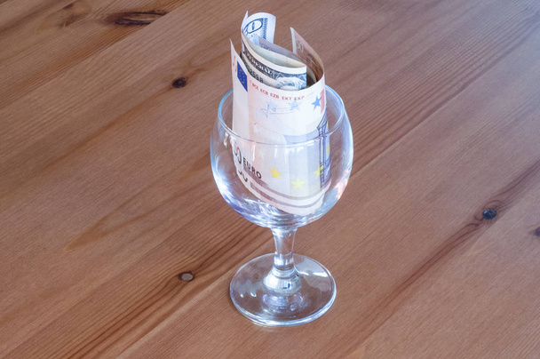 бокал вина на настольных монетах бумажные деньги, потраченные на алкоголь крупным планом
  - Фото, изображение