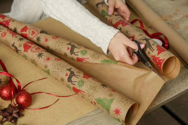 Женщина режет оберточную бумагу на столе, праздничный сезон подарочная концепция
 - Фото, изображение