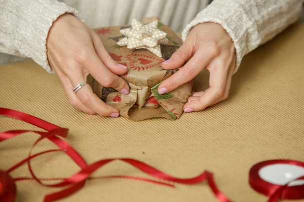 Женщина упаковывает рождественские подарки, зимние праздники, подарочная концепция сезона - Фото, изображение