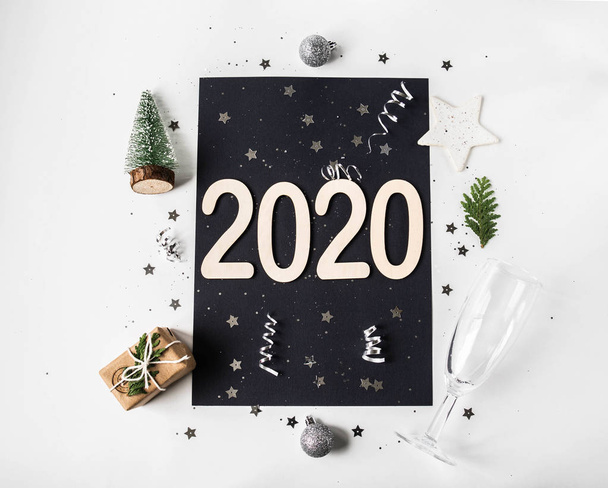 Düz beyaz yeni yıl kompozisyonu - siyah kart, beyaz arka plan, 2020 numara, Noel ağacı, şampanya bardağı, Noel baloları, hediye ve konfeti. Üst görünüm - Fotoğraf, Görsel