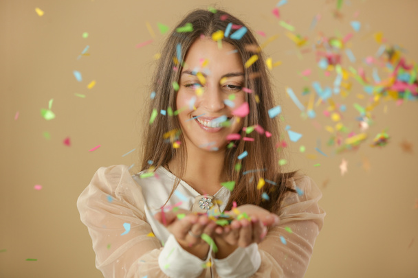 Retrato de uma bela jovem com as mãos cheias de confetes coloridos, festa e conceito de férias
 - Foto, Imagem