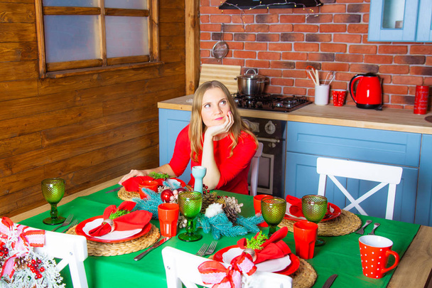 Uma bela jovem solitária sozinha na noite de Natal está triste na mesa festiva, porque ninguém veio visitá-la, Ano Novo, temporada de inverno.
 - Foto, Imagem