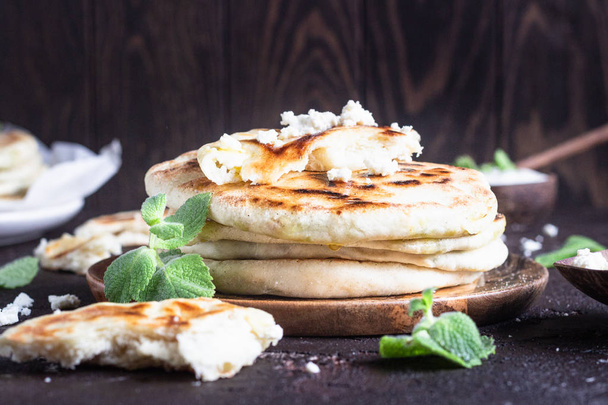 Onion, mint and cheese small flatbreads served on a wooden plate. Gozleme - crispy, golden Turkish flatbreads. - Fotó, kép