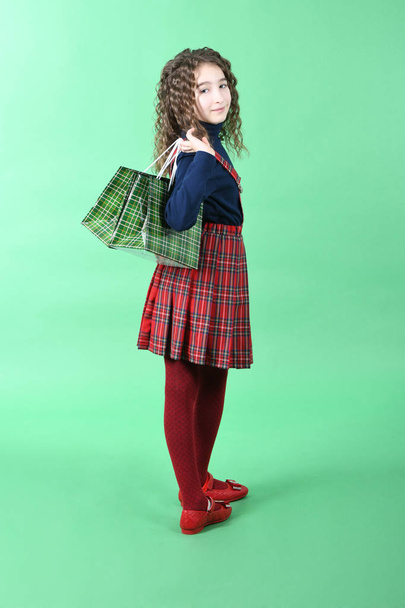 Child with a green packaging checkered texture isolated on green background. Girl likes shopping on sale season. Holiday present, shopping.  - 写真・画像