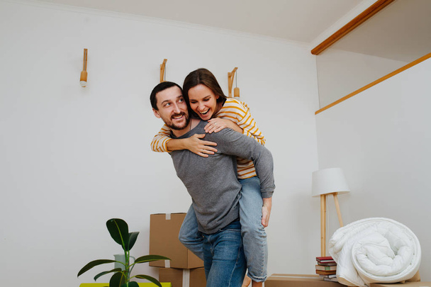 Couple celebrating moving into a new apartment. Woman riding on her man's back. - Foto, Imagem