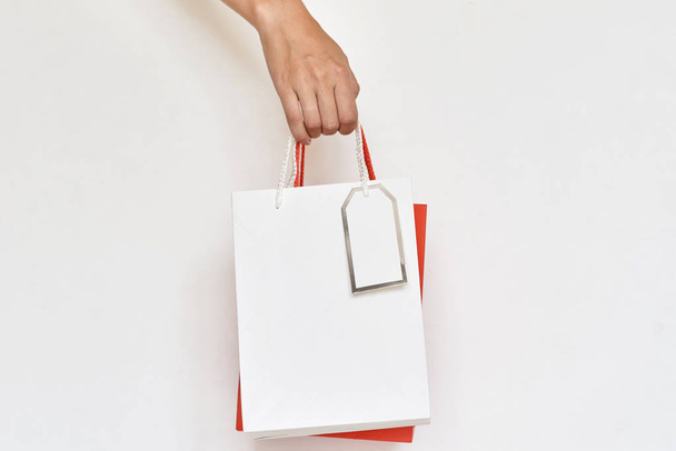 γυναίκα χέρι κρατήστε πολύχρωμο χαρτί τσάντες ψώνια σε ένα λευκό backgrou - Φωτογραφία, εικόνα