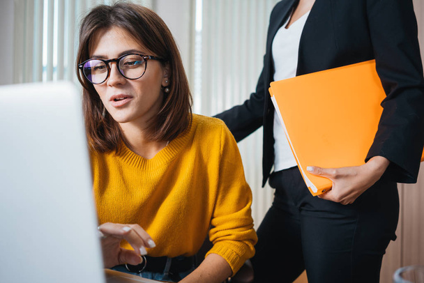 若いビジネス女性のチームは現代のオフィスで会合を持っています。職場でノートパソコンを使う2人の女性マネージャー - 写真・画像