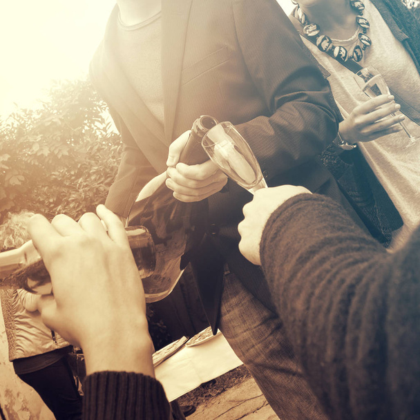 mladý dospělý nalévání víno těší s přáteli, detailní záběr akce (čtvercový obraz, vintage efekt) - Fotografie, Obrázek