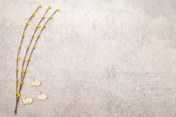 Artificial decorative willow twigs and wooden figures of bunny. The concept of Easter cards, wallpapers, stone background. Top view, copy space. - Foto, Imagem