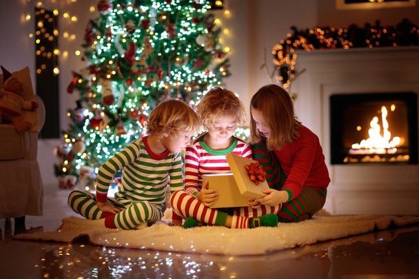 Gyermek a karácsonyfa. Gyerekek a kandalló a karácsonyi - Fotó, kép