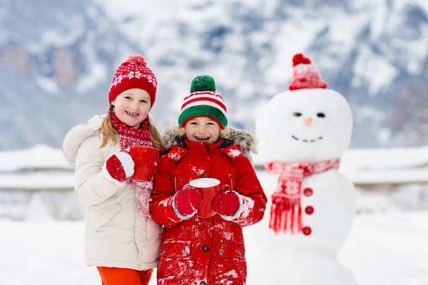 Детский снеговик. Дети строят снеговика
.  - Фото, изображение