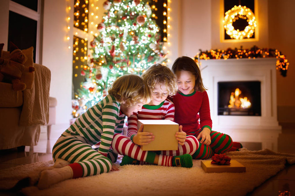 Child at Christmas tree. Kids at fireplace on Xmas - 写真・画像