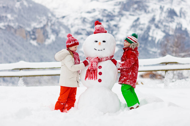 Child building snowman. Kids build snow man.  - 写真・画像