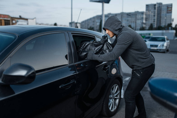 車泥棒はドアを壊す犯罪者は泥棒は盗む駐車中のフード付き男性強盗オープン車両。自動車強盗自動車犯罪 - 写真・画像