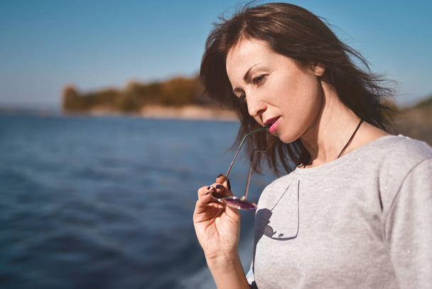 Retrato de una hermosa mujer adulta en el río del mar en el muelle. mujer pensó en algo importante
 - Foto, Imagen