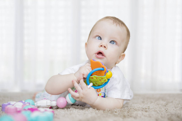 Cute baby girl holding a toy on the carpet - Foto, Imagem