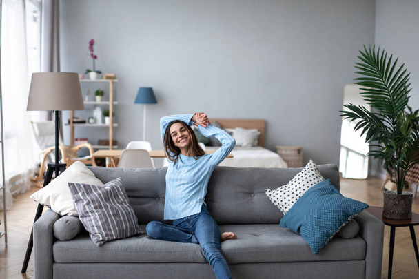 Happy casual beautiful woman sitting on a sofa at home.  - Fotó, kép