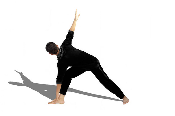 Full-length shot of male teenager practicing Revolved Yoga Pose or Revolved Triangle Yoga Pose or Parivrtta Trikonasana isolated on white background. - Zdjęcie, obraz